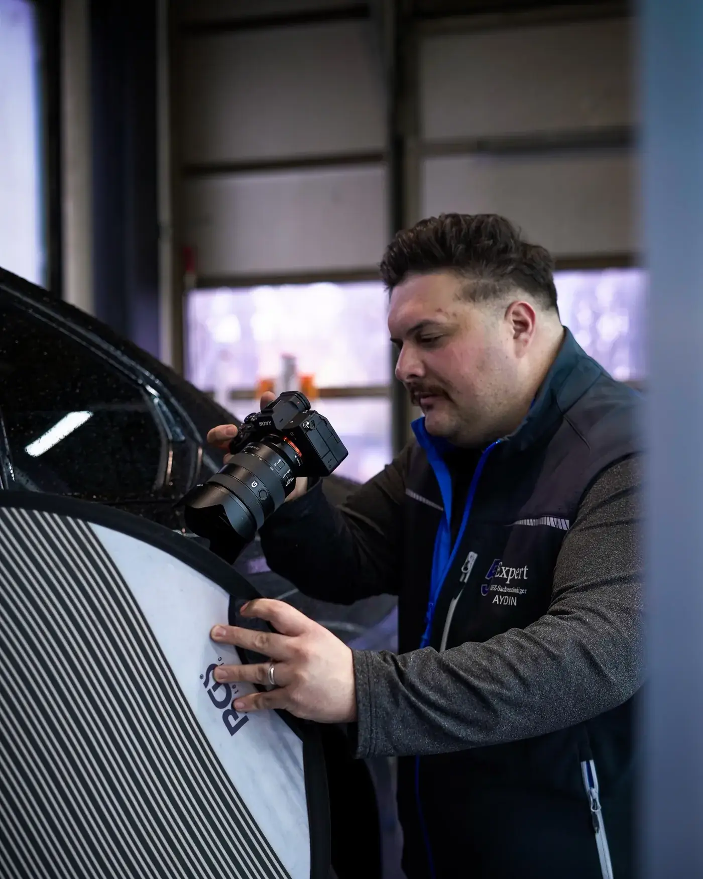 Okan Aydin, Kfz-Sachverständiger, bei der Schadendokumentation an einem Fahrzeug